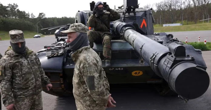 Екіпаж українського танку стоїть біля основного бойового танка Leopard 1A5, який навчають керувати та обслуговувати німецькі та датські військові на військовому полігоні Бундесверу, 5 травня 2023 року (Джерело фото: Шон Геллап )