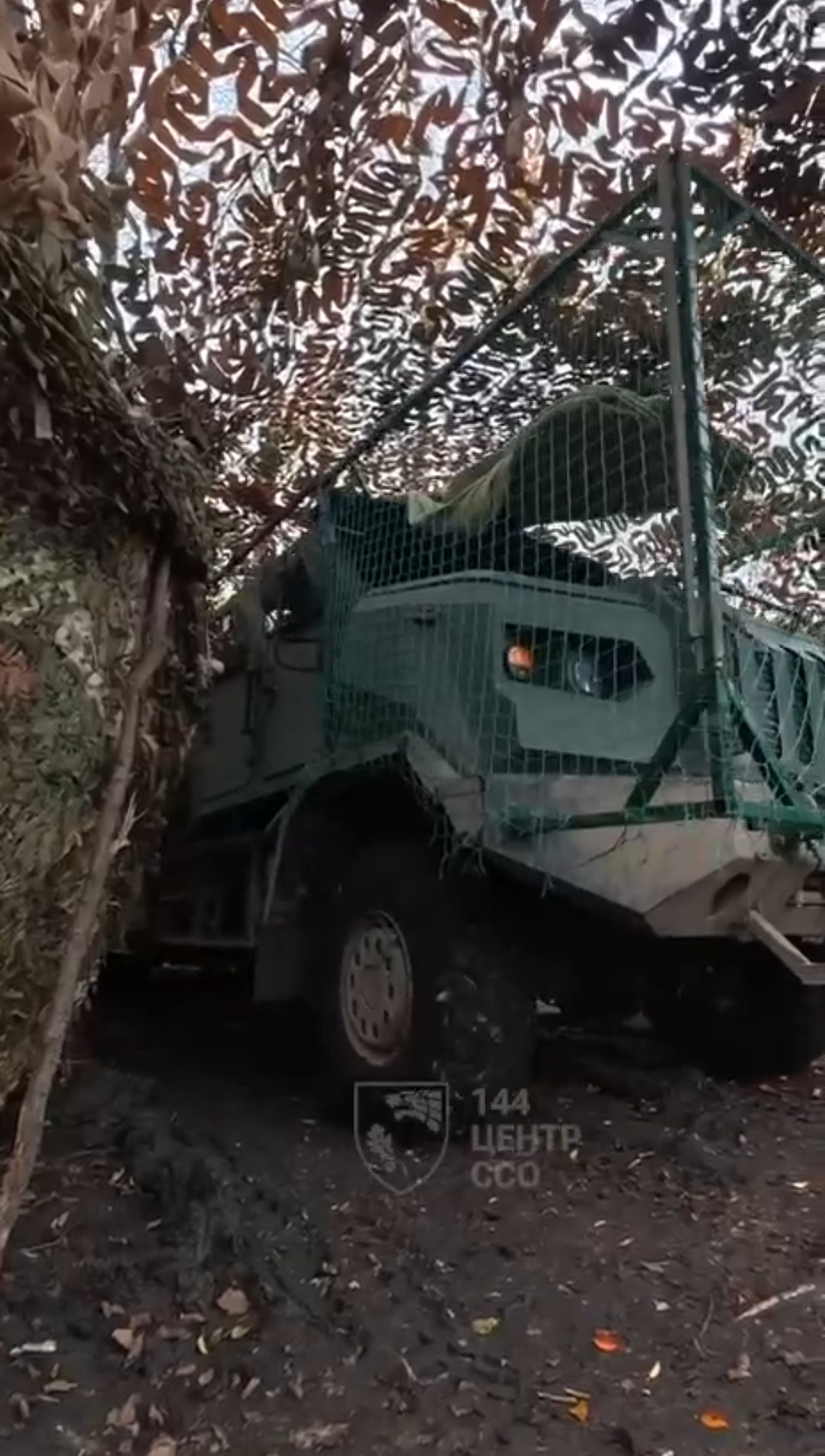 Володимир Бровченко, wheel-news.com Артилерійський дивізіон 144-го центру Сил спеціальних операцій отримав на озброєння українські самохідні артилерійські установки "Богдана" на новому шасі з колісною формулою 6×6. Раніше вони використовували радянську причіпну гаубицю "Мста-Б" калібру 152 мм - тепер змінили на сучасну українську техніку. На відео видно: САУ обладнана тканинним екраном для захисту кабіни й двигуна від FPV-дронів, а екіпаж озброєний не лише автоматами, а й дробовиками з картеччю - для збиття дронів. Ця конфігурація "Богдани" з новою броньованою кабіною та шасі 6×6 вперше показана публічно у вересні 2025-го. Зараз Україна виробляє 40 таких артсистем щомісяця. Від "Мсти-Б" до "Богдани": чому це важливо Командир гармати з позивним "Джек" розповів: до цього його розрахунок використовував радянську причіпну гаубицю "Мста-Б" калібру 152 мм. Це надійна зброя, яка пережила десятиліття, але вона має критичні недоліки: Причіпна конструкція - потрібен тягач, щоб пересуватися. Час на розгортання й згортання позиції більший. Відсутність броньованого захисту - екіпаж на відкритому повітрі, вразливий до осколків і дронів. Калібр 152 мм - боєприпаси важкі, складніше в логістиці. "Богдана" - це самохідна артилерійська установка калібру 155 мм (стандарт НАТО). Вона мобільна, швидко розгортається, швидко згортається, має броньовану кабіну. Час реакції на контрбатарейний вогонь значно коротший - а це різниця між життям і смертю. Шасі 6×6: нова конфігурація для важких умов "Богдана" на шасі 6×6 - це модифікація, яка вперше публічно показана у вересні 2025 року пресслужбою 60-ї окремої артилерійської бригади. Раніше "Богдану" випускали на шасі 8×8 (КрАЗ) та інших платформах. Чому 6×6? Це компроміс між прохідністю й масою. Менше осей - менша вага, вища мобільність на твердому грунті. Але все ще достатньо прохідності для важких умов: грязь, сніг, розбиті дороги. Нова броньована кабіна захищає екіпаж від осколків, куль і дронів-камікадзе. Це не танкове бронювання, але краще, ніж нічого. Тканинний захист від FPV: дешево й ефективно На відео видно: "Богдану" обладнали тканинним екраном для захисту кабіни й двигуна від FPV-дронів. Це не броня, а сітка або тент, який деформує траєкторію дрона або передчасно підриває заряд, зменшуючи ушкодження. Це дешеве рішення, яке працює. FPV-дрони - одна з найбільших загроз для техніки на передовій. Тканинні екрани, решітки, каркаси - усе це знижує ефективність атак. Дробовики проти дронів: новий стандарт Екіпаж "Богдани" озброєний не лише автоматами, а й гладкоствольними рушницями з дробовими набоями. Це для збиття FPV-дронів на підльоті. Автомат ефективний проти піхоти, але збити дрон із нього складно. Дробовик - інша справа: широкий розлітання дробу, велика ймовірність влучення. Один постріл - і дрон падає. Це вже стандартна практика на передовій. Кожен розрахунок артилерії має дробовики в комплекті. Це частина протидронової оборони. 40 "Богдан" щомісяця: рекордні темпи виробництва На початку жовтня президент Володимир Зеленський заявив, що українська промисловість виробляє 40 артилерійських систем "Богдана" щомісяця. Ймовірно, йдеться про самохідні та причіпні версії разом. "Ми змогли рекордно швидко й якісно налагодити виробництво нашої вітчизняної артилерії. Тільки "Богдан" ми виробляємо вже 40 на місяць. Це серйозний результат. Дякуємо виробникам", - сказав Зеленський під час Defence Industries Forum DFNC³. 40 САУ на місяць - це майже 500 на рік. Це масштаб, якого важко досягти навіть великим країнам. Україна зробила це за два роки повномасштабної війни. Чому це важливо для ССО Сили спеціальних операцій зазвичай не асоціюються з важкою артилерією. Але війна змінила пріоритети. ССО потребують вогневої підтримки для операцій у тилу ворога, на важкодоступних напрямках, у важких умовах. "Богдана" на шасі 6×6 - ідеальний варіант для ССО: мобільна, швидка, захищена, здатна швидко нанести удар і піти з позиції. Це не статична артилерія, яка стоїть на одному місці. Це мобільна вогнева підтримка. Висновок: українська артилерія наздоганяє "Богдана" на шасі 6×6 у ССО - це символ того, як українська оборонна промисловість наздоганяє потреби фронту. Від радянської причіпної "Мсти-Б" до сучасної самохідної САУ з броньованою кабіною, захистом від дронів і дробовиками в комплекті. 40 таких систем щомісяця - це не просто цифра. Це результат роботи тисяч людей: конструкторів, інженерів, робітників, логістів. Це доказ, що Україна здатна виробляти зброю світового рівня. І це лише початок. Бо війна не закінчилася, а виробництво продовжує зростати.